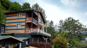 a wooden house with a balcony on the side of it at The Door to Nirvana Backpackers Hostel Kotagiri in Kotagiri