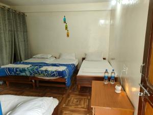 a room with two beds and a table and two bottles of water at Sajjus Riverside Retreat in Manāli