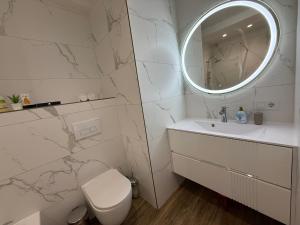 a white bathroom with a toilet and a mirror at Apartamentul white Arena in Chişinău