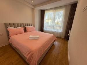 a bedroom with a bed with pink sheets and a window at Apartamentul white Arena in Chişinău +9 photos