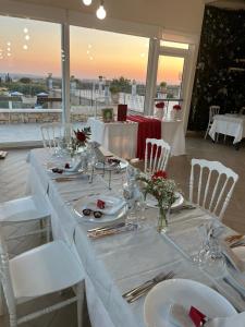 a long table with white tables and white chairs at Agriturismo Valle di Chiaramonte in Chiaramonte Gulfi