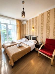 a bedroom with two beds and a red chair at Hotel Marioni in Tbilisi City