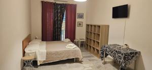 ein Schlafzimmer mit Bett, Tisch und Fernseher in der Unterkunft Affittacamere Nilo in Neapel