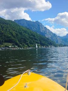a yellow boat on a lake with mountains in the background at MEGA WEEKEND Apartment in Salzkammergut Nähe Attersee Traunsee Gmunden Bergen in Attnang-Puchheim