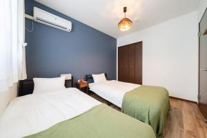 a bedroom with two beds and a blue wall at Value residence Kugai 3A in Miyako-jima