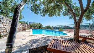 a swimming pool with a bench and a tree at Villa Matej by Villas Guide in Zaton