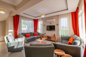 a living room with couches and red curtains at Sureyya Hotel By Kalipso in Oludeniz