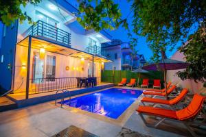 a house with a swimming pool with chairs and an umbrella at Sureyya Hotel By Kalipso in Oludeniz