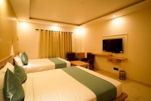 a hotel room with two beds and a flat screen tv at Shree Goljyu Palace in Almora