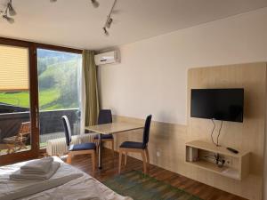 a hotel room with a bed and a table and a television at Appartements Domizil in Kaprun