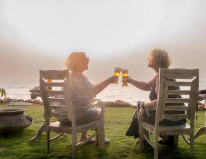 two people sitting in chairs drinking beer by the ocean at Refuge Boutique Villa in Hikkaduwa