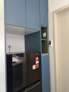 a kitchen with a black refrigerator and a blue wall at Sufi Idaman Homestay for Islamic only in Nilai