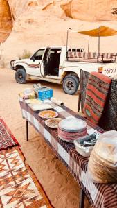 a table in the desert with a truck in the background at Wadi Rum Luxury Hamad & Jeep Tours in Wadi Rum