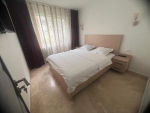 a small bedroom with a white bed and a window at Ywa in Râmnicu Vâlcea