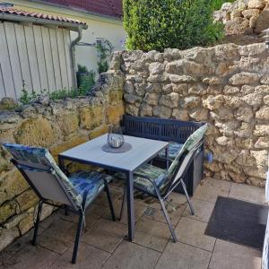 a table and two chairs sitting next to a stone wall at Ferienwohnung Kemmerth in Ebermannstadt