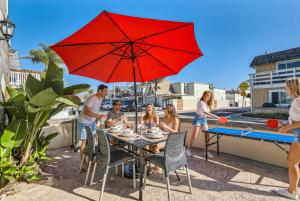 a group of people sitting around a table with a red umbrella at Awesome 3BR 2BTH 1 Block To Beach C2 in Newport Beach