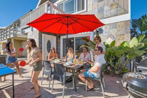 a group of people sitting around a table under a red umbrella at Awesome 3BR 2BTH 1 Block To Beach C2 in Newport Beach