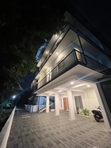 a large white building with a balcony at night at Orbis Rooms & Apartments in Kakkanad