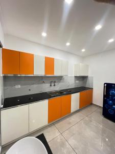 a kitchen with orange and white cabinets and a sink at Orbis Rooms & Apartments in Kakkanad +8 photos