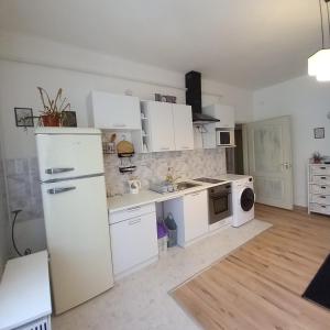 a kitchen with white cabinets and a white refrigerator at Lucia apartman in Kaposvár