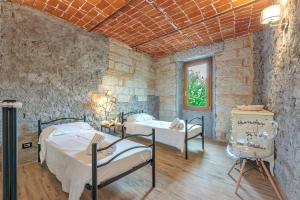 a bedroom with two beds and a stone wall at Cascina Liebe con Idromassaggio in Ozzano Monferrato