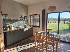 a kitchen with a table and chairs and a large window at Gospodarstwo agroturystyczne Pod Wielkim Wozem in Jerutki
