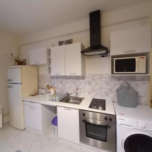 a kitchen with white cabinets and a sink and a microwave at Lucia apartman in Kaposvár +7 photos