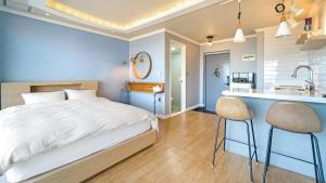 a blue bedroom with a bed and a kitchen at Baradeon Bada Pension, Yangyang in Yangyang