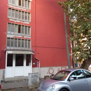 a car parked in front of a red building at Lucia apartman in Kaposvár