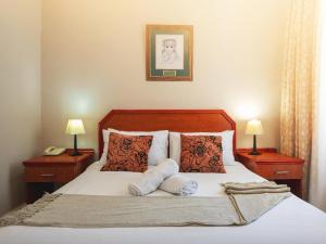 a bedroom with a bed with pillows and two lamps at Oak lodge Guest House in Grahamstown +57 photos