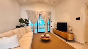 a living room with a white couch and a tv at Pipa Sunset Home in Pipa