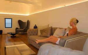 a woman sitting on a couch in a living room at Refuge Boutique Villa in Hikkaduwa