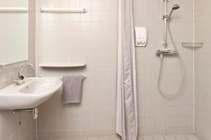 een witte badkamer met een douche en een wastafel bij Hotel Marenland Winsum in Winsum