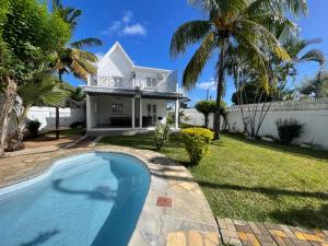 a villa with a swimming pool in front of a house at Villa Roche Noire with Pool- 4 mins from Beach in Tamarin