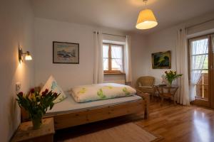 a living room with a bed and a table with flowers at Gästehaus Heiß in Lenggries