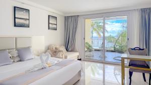 a white bedroom with a bed and a balcony at Ocean Star Hotel in Koror