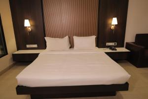 a bedroom with a large bed with white sheets and pillows at The Ashoka Hotel in Howrah