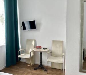 two chairs and a table with a tv on a wall at Hotel Lübecker Hof in Lüneburg