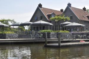 un restaurante con mesas y sombrillas junto al agua en Hotel Marenland Winsum en Winsum
