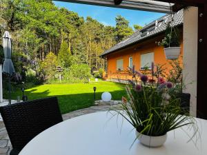 a patio with a table and chairs and a yard at Ferienwohnung Am Waldesrand - Garten, Terrasse, Grill, Luftkühler, Massagesessel, Kinderspielecke, Spielekonsole in Cottbus