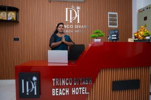 a woman standing at a red counter in a room at Trinco Diyash Beach Hotel in Trincomalee