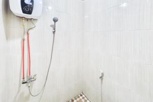 a shower in a white tiled bathroom with a camera at Urbanview Hotel MD Residence in Sunggal +13 photos