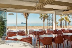a restaurant with tables and chairs on the beach at Les Dunes Comodoro in Benidorm