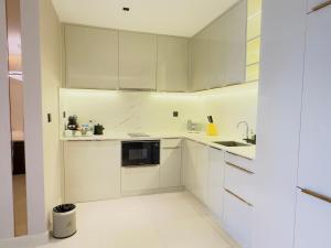 a white kitchen with white cabinets and a sink at P Residence Phnom Penh in Phnom Penh