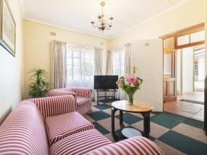 a living room with two couches and a table with flowers at Oak lodge Guest House in Grahamstown
