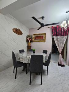a dining room with a table and chairs and a ceiling fan at Homestay Iliana in Kangar