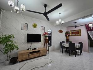 a living room with a television and a table with chairs at Homestay Iliana in Kangar
