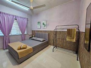 a bedroom with a bed with purple curtains at Homestay Iliana in Kangar