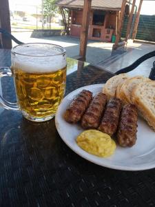 a plate of sausage and bread and a glass of beer at Pensiunea Casa Cora in Stupăreni