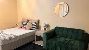a bedroom with a green couch and a mirror at Zak Guest House in Manzini